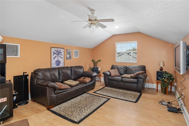 living room with baseboards, visible vents, vaulted ceiling, a textured ceiling, and light wood-style floors