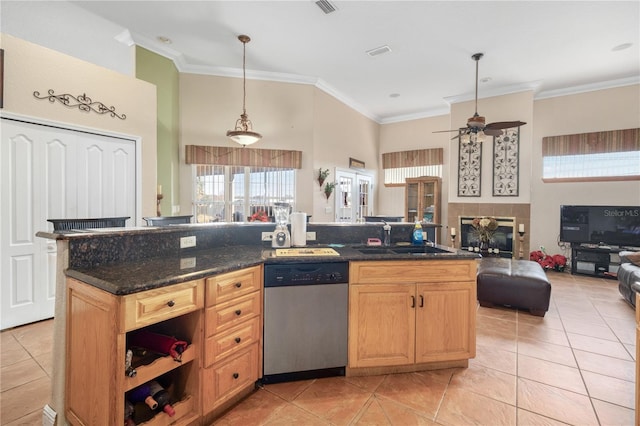 kitchen with dark stone counters, dishwasher, open floor plan, decorative light fixtures, and a sink