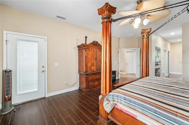 bedroom featuring dark wood-style flooring, a ceiling fan, baseboards, visible vents, and ornate columns