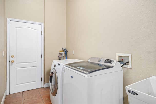 clothes washing area with light tile patterned floors, laundry area, separate washer and dryer, and a sink