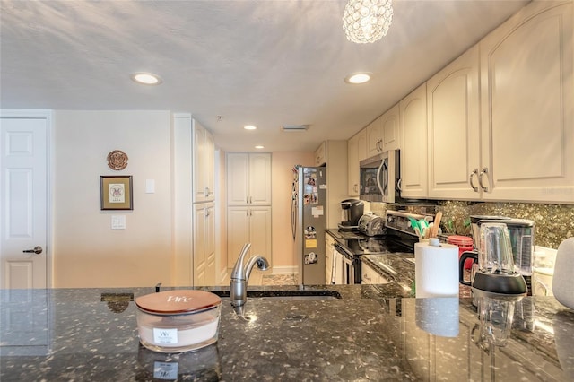 kitchen with stainless steel appliances, recessed lighting, backsplash, a sink, and dark stone countertops