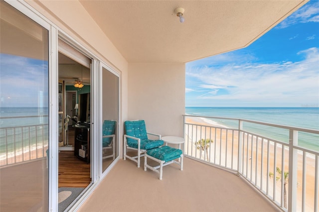 balcony featuring a sunroom, a water view, and a view of the beach