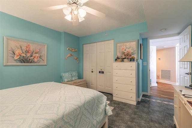 bedroom with a closet, visible vents, ceiling fan, dark tile patterned flooring, and baseboards