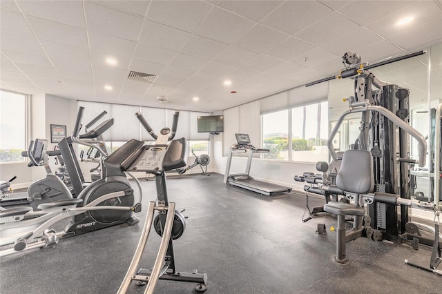 exercise room featuring a paneled ceiling, recessed lighting, visible vents, and baseboards