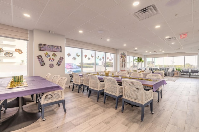 dining area featuring a paneled ceiling, visible vents, and a wealth of natural light