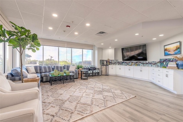 living room with recessed lighting, visible vents, a drop ceiling, and light wood finished floors