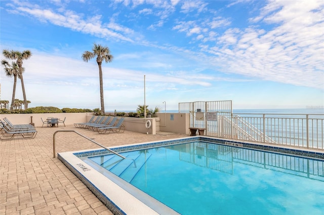 community pool with a patio and a water view