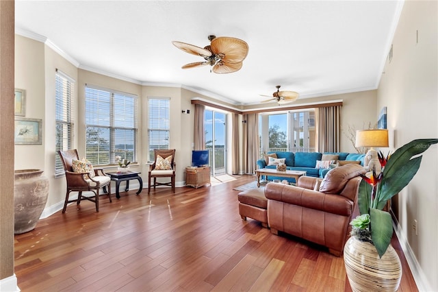 living room featuring crown molding, wood finished floors, a ceiling fan, and baseboards