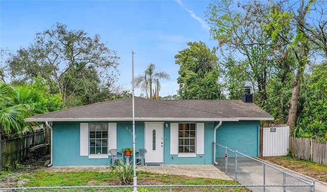 view of front of home with a chimney, roof with shingles, fence, a porch, and stucco siding