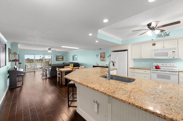 kitchen featuring dark wood-style flooring, ornamental molding, white cabinets, a sink, and white appliances