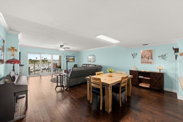 dining room featuring dark wood-style flooring, crown molding, a ceiling fan, a textured ceiling, and baseboards