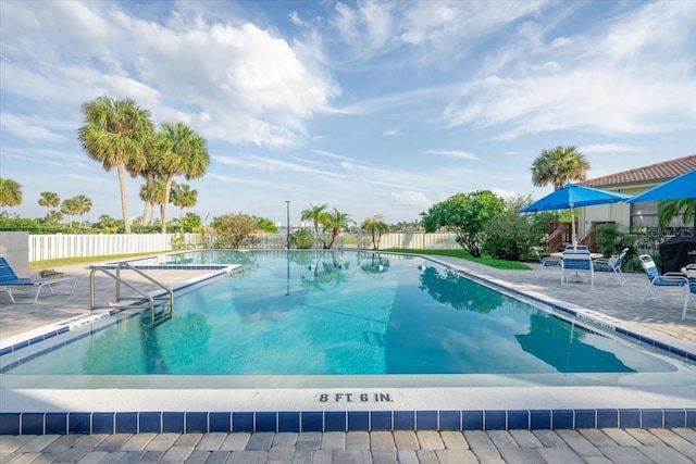 pool with a patio area and fence