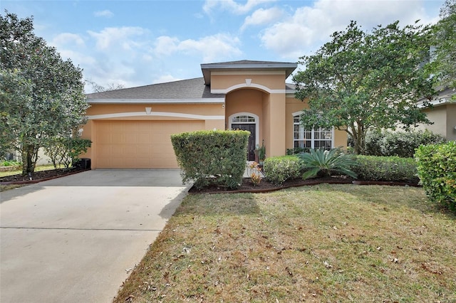 view of front of home with a front yard, concrete driveway, an attached garage, and stucco siding