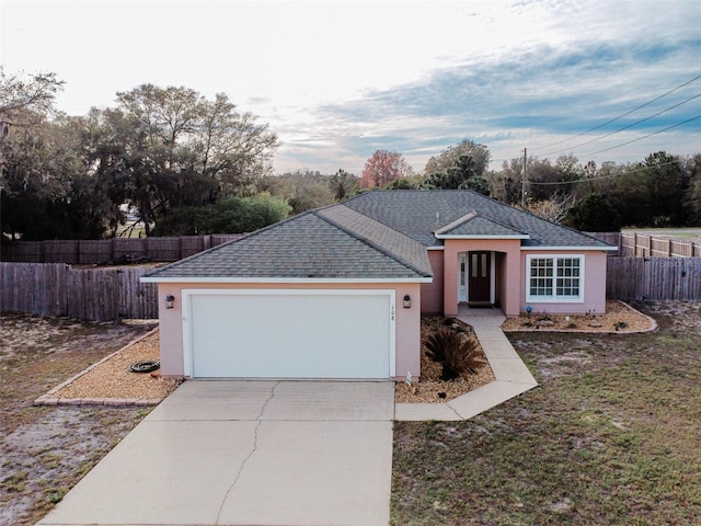 ranch-style house with a garage, fence, driveway, roof with shingles, and stucco siding