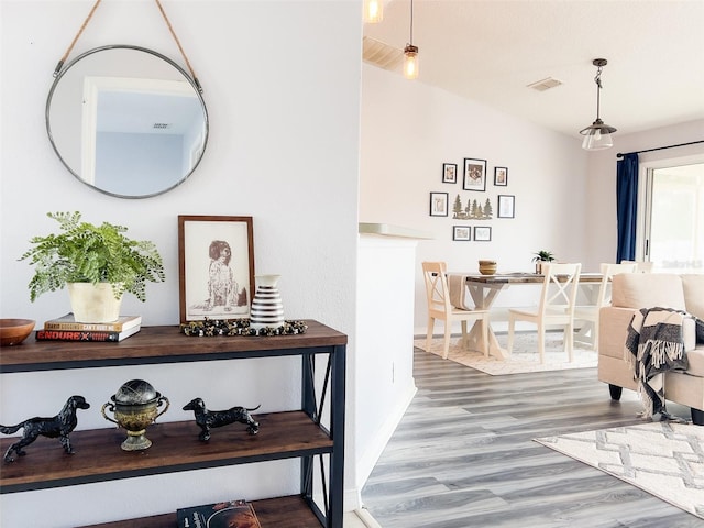 hallway featuring baseboards, visible vents, and wood finished floors