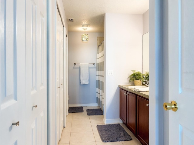 bathroom with visible vents, vanity, a textured ceiling, tile patterned flooring, and baseboards