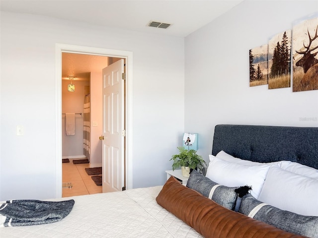 bedroom featuring light tile patterned flooring, ensuite bath, and visible vents