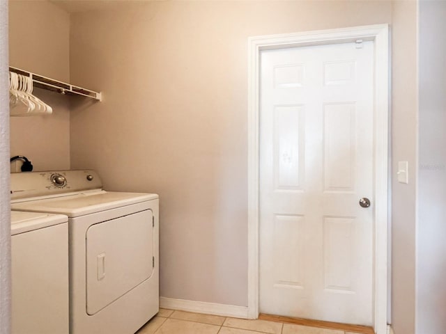 washroom with washing machine and dryer, laundry area, light tile patterned flooring, and baseboards