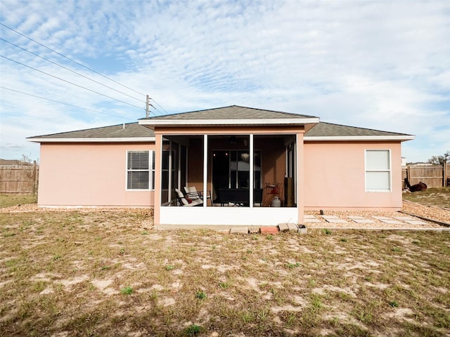 rear view of property with a sunroom, fence, stucco siding, and a yard