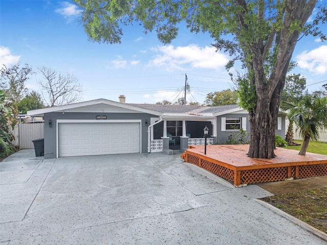 ranch-style house with driveway, a wooden deck, an attached garage, and stucco siding