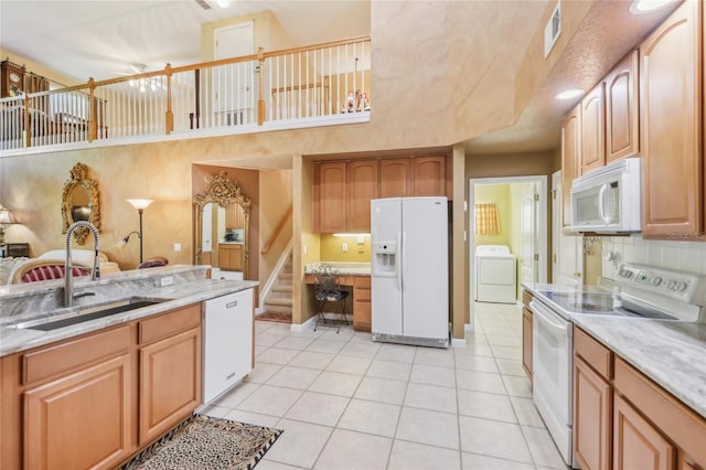 kitchen featuring visible vents, decorative backsplash, white appliances, washer / clothes dryer, and a sink