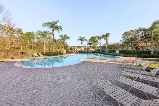 community pool with a patio and fence