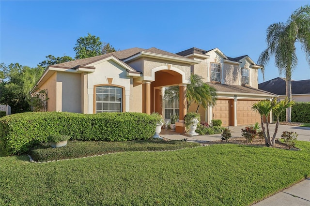 mediterranean / spanish-style home with stucco siding, a front yard, concrete driveway, and an attached garage