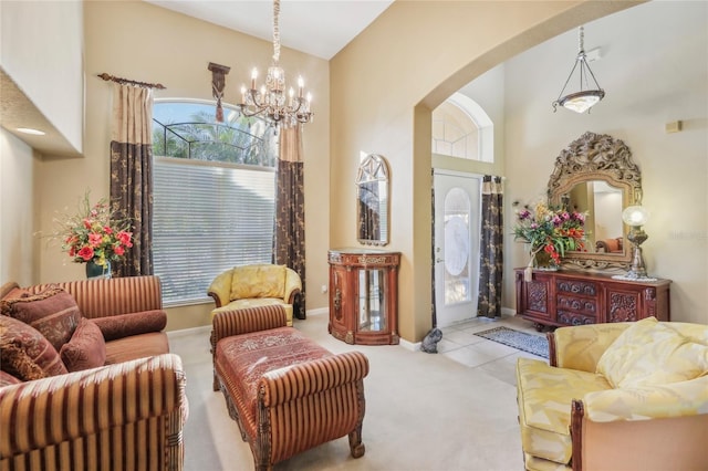 living area featuring baseboards, carpet floors, a high ceiling, arched walkways, and a chandelier