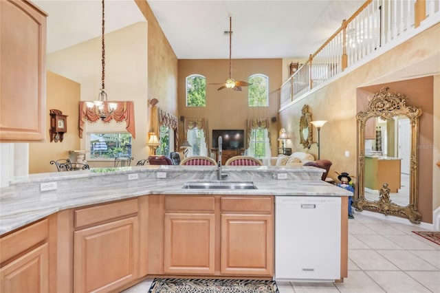 kitchen with a sink, light stone counters, dishwasher, and open floor plan