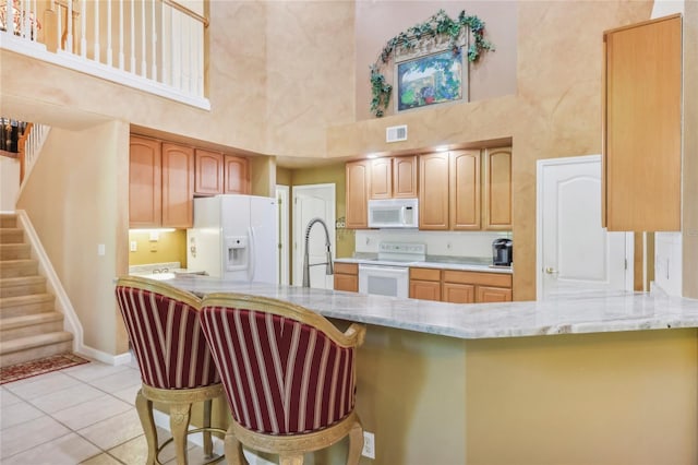 kitchen featuring visible vents, light stone countertops, light tile patterned floors, a peninsula, and white appliances