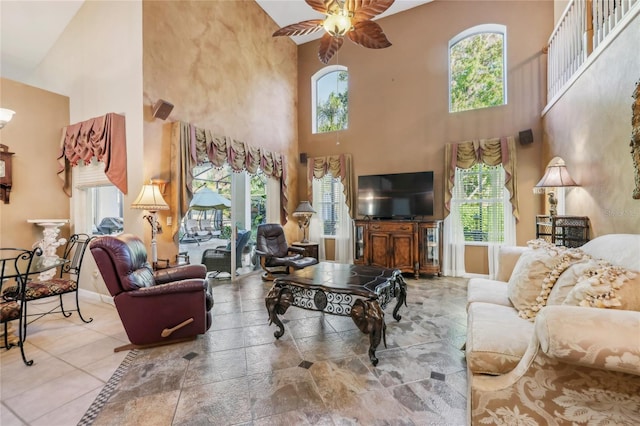 living area with a healthy amount of sunlight, baseboards, a high ceiling, and ceiling fan