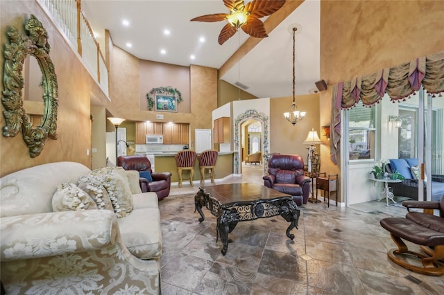 living room with baseboards, recessed lighting, a towering ceiling, stone finish flooring, and ceiling fan with notable chandelier