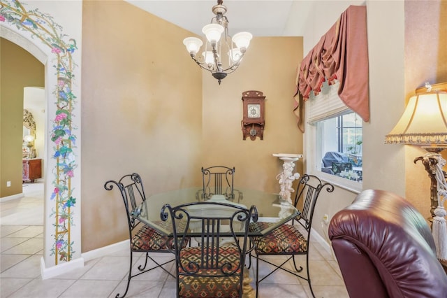 tiled dining space featuring baseboards, arched walkways, and a notable chandelier