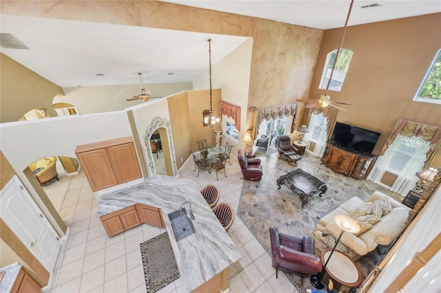 living room featuring visible vents, high vaulted ceiling, ceiling fan with notable chandelier, arched walkways, and light tile patterned flooring