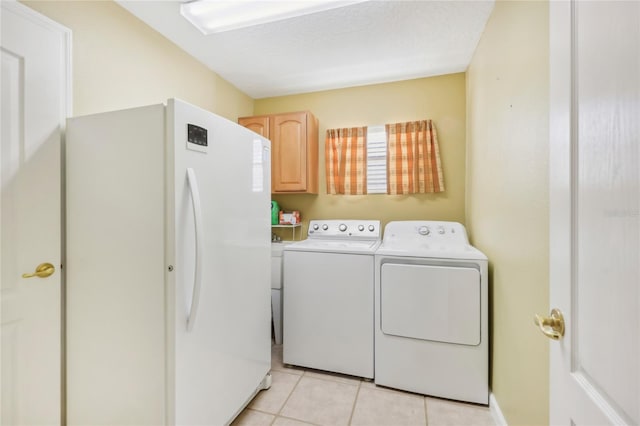 clothes washing area featuring light tile patterned floors, cabinet space, and separate washer and dryer