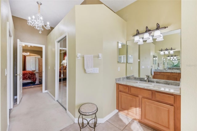 full bath with baseboards, vanity, an inviting chandelier, tile patterned floors, and ensuite bath