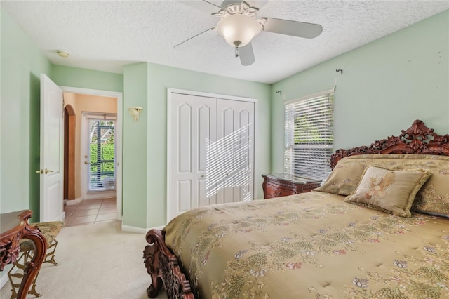 bedroom with a closet, multiple windows, a textured ceiling, and light colored carpet