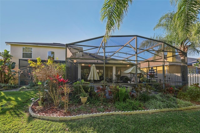 rear view of property featuring glass enclosure and stucco siding