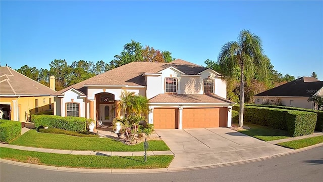 view of front of property featuring a front lawn, a garage, driveway, and stucco siding