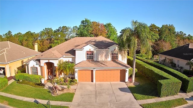 view of front of home with stucco siding, a front lawn, a garage, and driveway