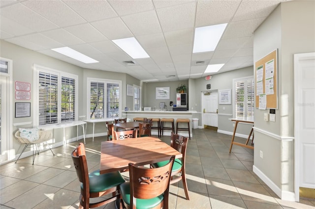 dining room featuring a drop ceiling, visible vents, plenty of natural light, and baseboards