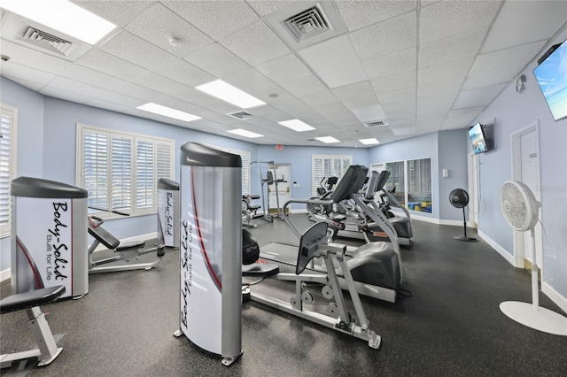 gym featuring visible vents, a healthy amount of sunlight, a paneled ceiling, and baseboards