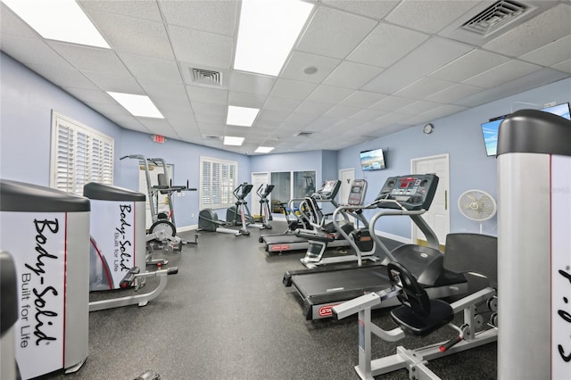 workout area featuring visible vents, a paneled ceiling, and baseboards