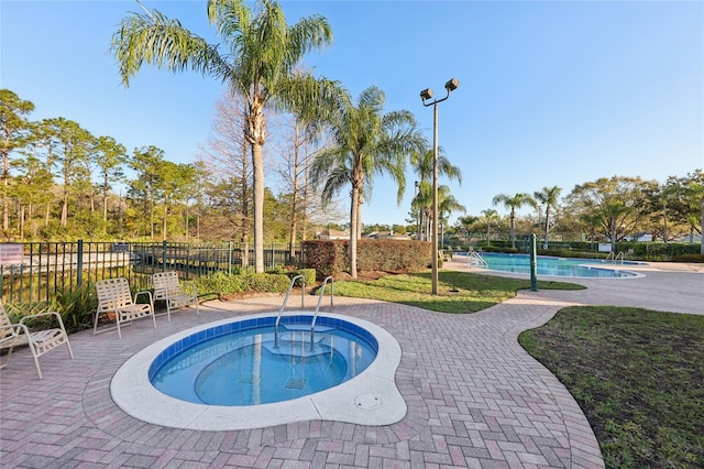 pool featuring a community hot tub, a patio, and fence