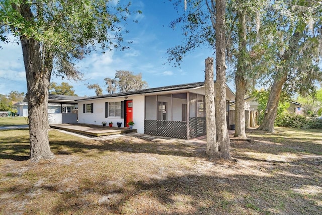 ranch-style house with a front yard, a sunroom, and a deck