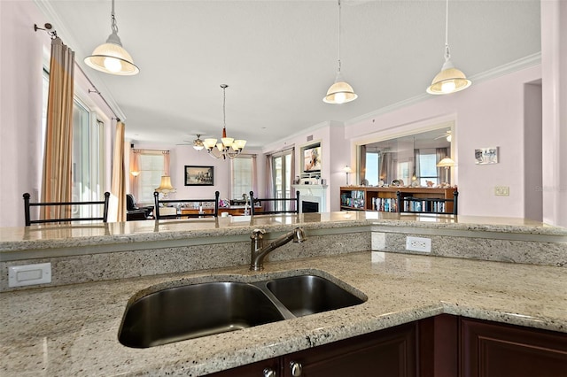 kitchen with light stone countertops, plenty of natural light, pendant lighting, and a sink