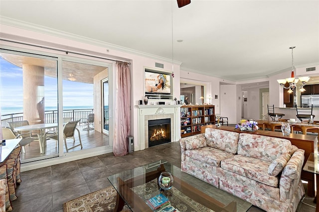 living area featuring a water view, a chandelier, a tiled fireplace, and ornamental molding