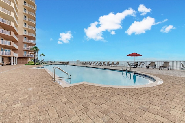 pool featuring a patio area, a water view, and fence