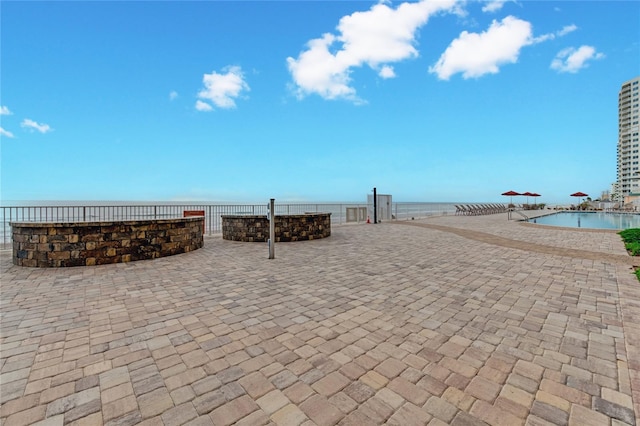 view of patio with a water view and fence