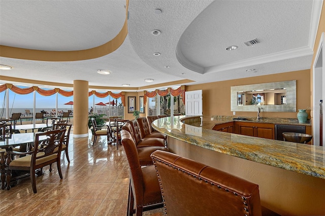 interior space with a tray ceiling, black dishwasher, light tile patterned floors, visible vents, and a textured ceiling